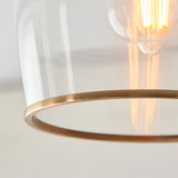Close-up of the Halstead flush ceiling light showing the clear glass shade with an aged brass rim and visible E27 bulb filament.