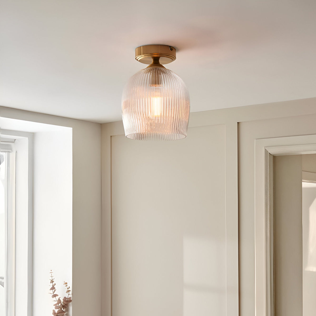 Endon Halstead flush ceiling light with ribbed glass shade and aged brass fitting, mounted on a hallway ceiling beside a cream panelled wall.