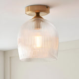Endon Halstead flush ceiling light with ribbed clear glass dome shade and aged brass fitting, mounted to a white ceiling above a pale wall.