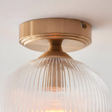 Endon Halstead flush ceiling light in aged brass with a ribbed clear glass globe shade, mounted close to a white ceiling.