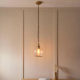 Halstead Pendant in brass with a clear glass dome shade and exposed bulb, hung on a chain in a softly lit dining room setting.