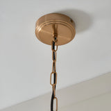 Halstead Pendant in brass shows a round ceiling rose with a brushed brass finish, linked chain, and black braided flex against a white ceiling.