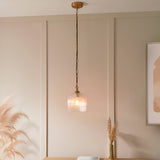 Endon Halstead ribbed single pendant with fluted clear glass dome shade and brass chain suspension, hung against a panelled beige wall above a console.