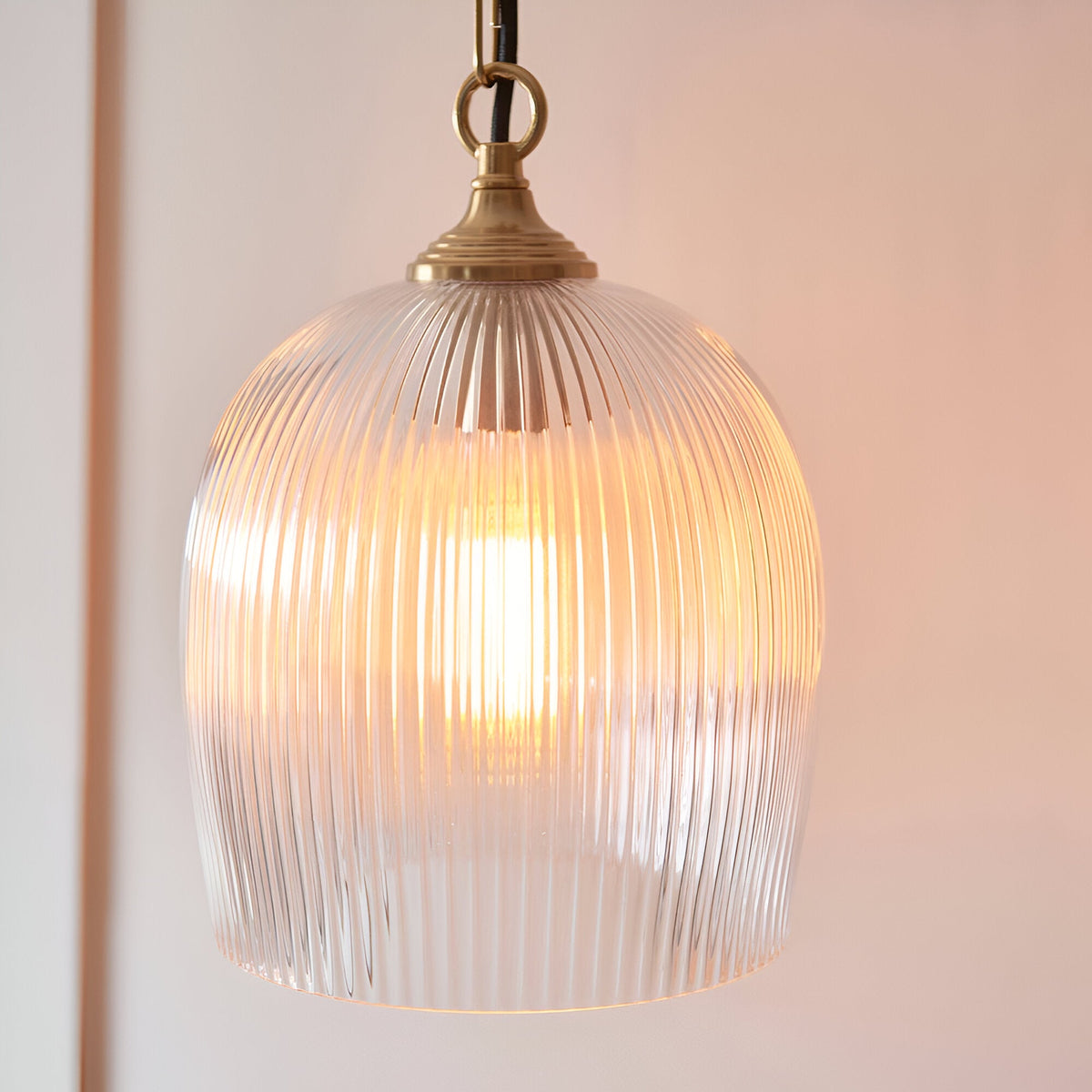 Endon Halstead ribbed single pendant with fluted clear glass dome shade in brushed brass, suspended from a black braided flex and chain.
