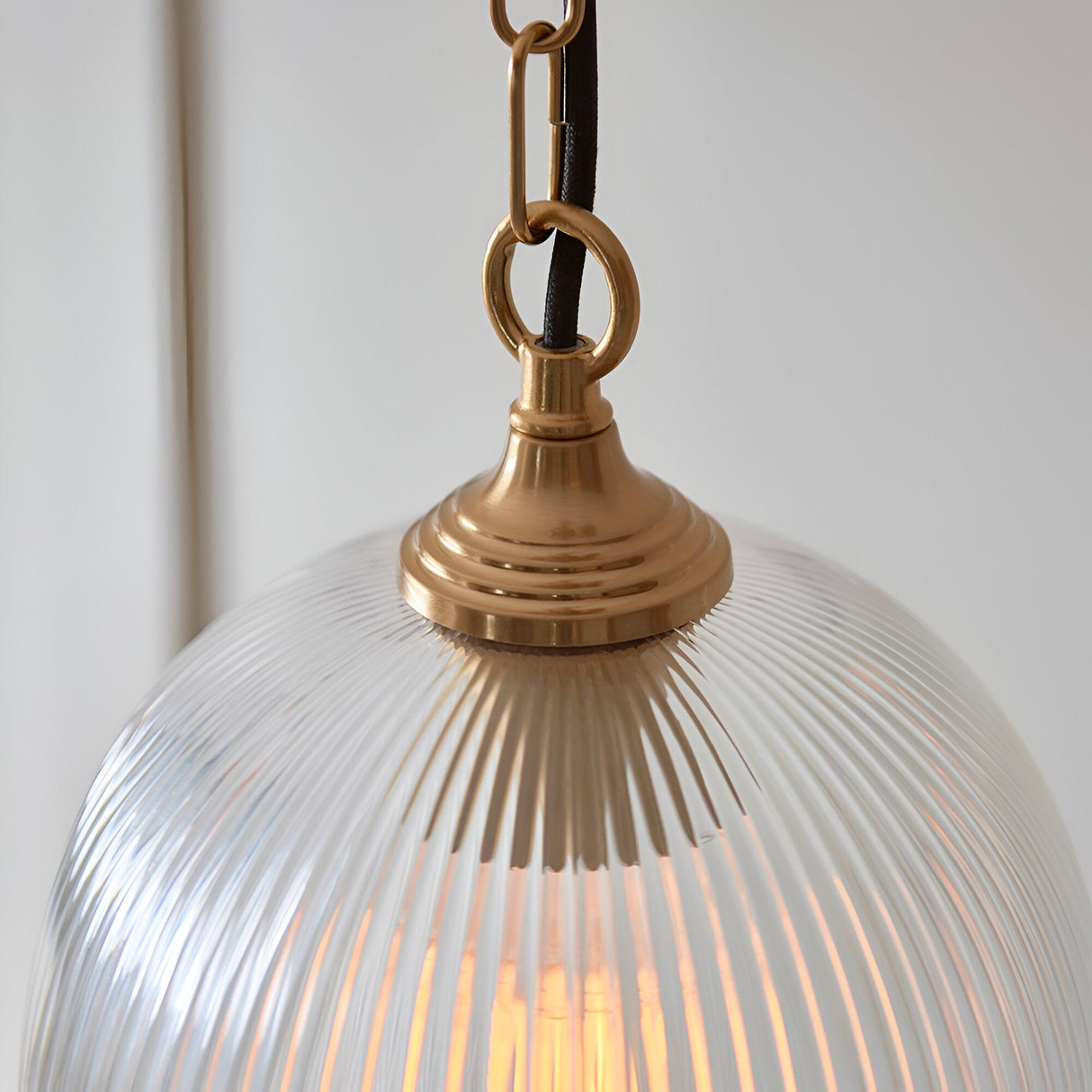 Close-up of Endon Halstead Ribbed Pendant in brass, showing the fluted clear glass dome shade, brushed brass cap and chain with black braided flex.