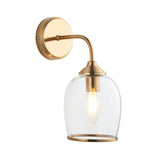 Halstead Wall Light in brushed brass finish, with a curved arm, round back plate, and clear domed glass shade housing an E14 bulb, shown on a white background.
