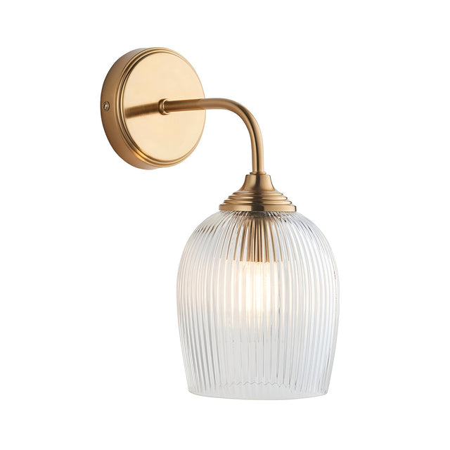 Endon Halstead Ribbed wall light with a brushed brass curved arm, round back plate and clear fluted glass domed shade, on a white background.