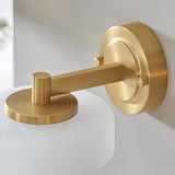 Close-up of the Endon Ashby brushed brass wall light showing the circular backplate, adjustable arm, and top of the frosted glass shade.