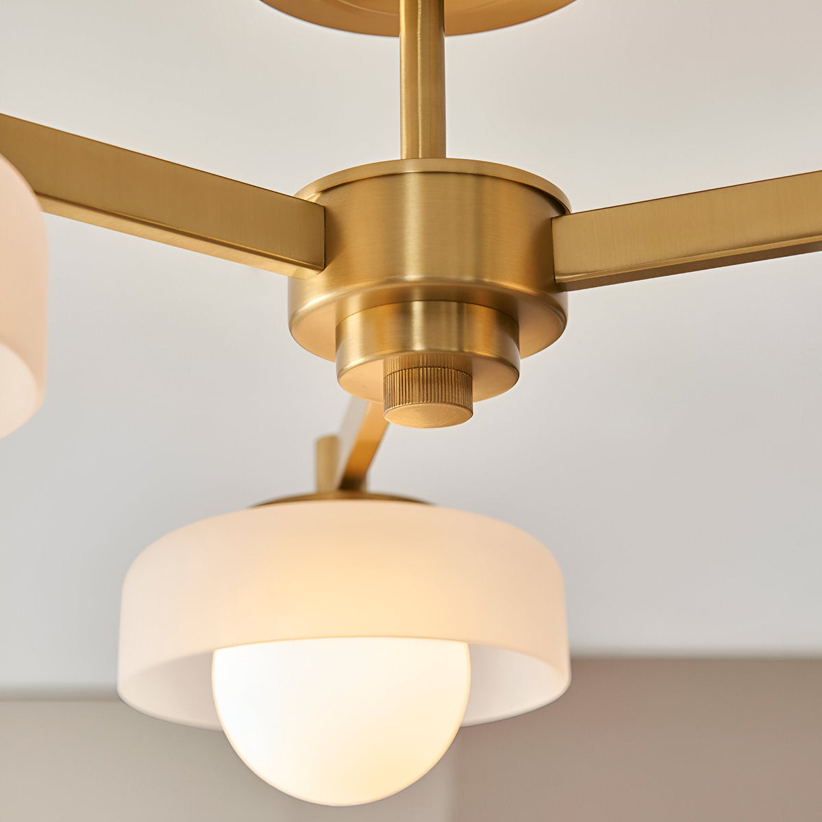 Close-up of the Endon Ashby semi-flush ceiling light showing its aged brass central hub, arms, and opal glass shade with G9 lamp beneath.