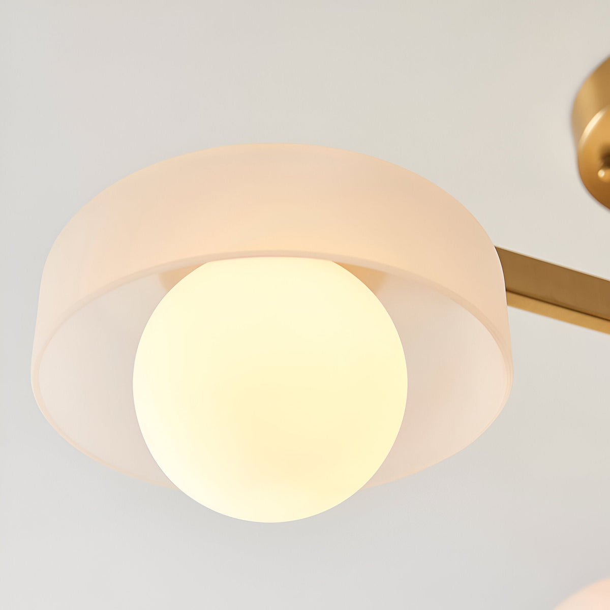 Close-up of Endon Ashby semi-flush ceiling light showing a frosted glass shade with illuminated G9 globe on an aged brass arm.