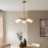 Endon Ashby 5 light pendant in brushed aged brass with frosted glass shades and opal globes, above a dining table in a neutral room.