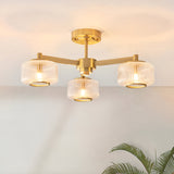 Endon Rutland 3 light semi-flush ceiling light in aged brass with ribbed glass shades on three arms, mounted to a pale ceiling.