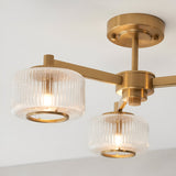 Endon Rutland semi-flush ceiling light in aged brass, shown close-up with ribbed glass shades on angled arms fixed to a round ceiling plate.