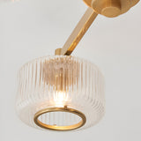 Close-up of one ribbed glass shade with aged brass ring and arm on the Endon Rutland 3 Light Semi-Flush Ceiling Light, lit G9 lamp visible inside.