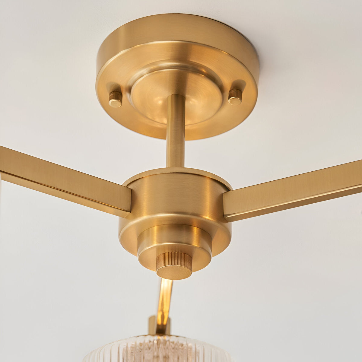 Close-up of the Endon Rutland semi-flush ceiling light showing the aged brass canopy, central hub and three arms against a white ceiling.