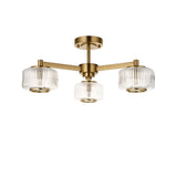 Endon Rutland 3 light semi-flush ceiling light in aged brass with ribbed glass shades on three arms, shown on a white background.