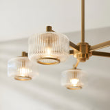 Rutland 5 Light Pendant in brushed aged brass, with clear ribbed glass shades and brass trim rings, shown close-up against a light background.