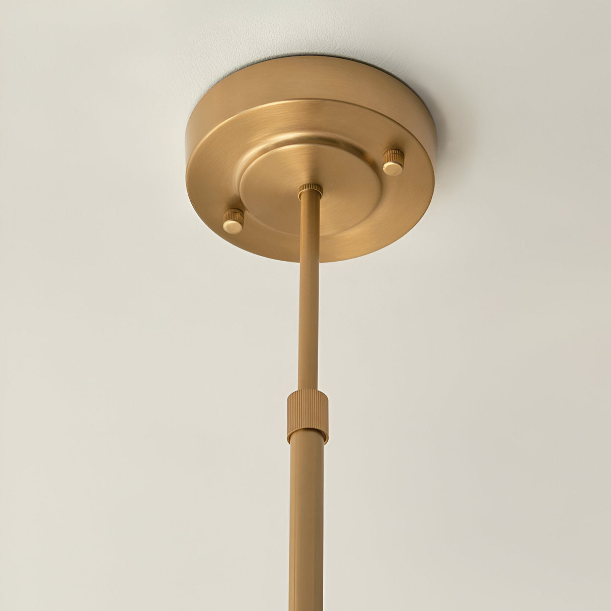 Rutland 5 Light Pendant in brushed aged brass, close-up of ceiling rose and adjustable telescopic stem, plain light background.