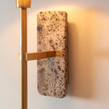 Bramble Wall Light with mottled stone backplate and brass arm, mounted on a light wall showing a warm ambient glow.