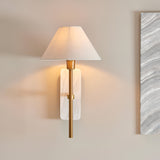 Bramble Wall Light with a marble backplate, brass-toned arm and tapered white linen shade, mounted on a neutral wall beside a marble-effect panel.