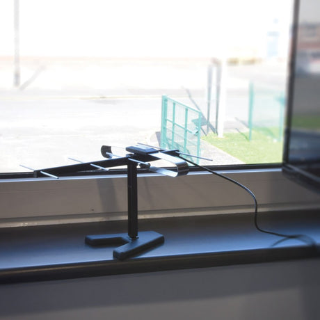 Mercury ST01-C indoor UHF aerial with black stand and metal directional elements, positioned on a windowsill overlooking a car park.