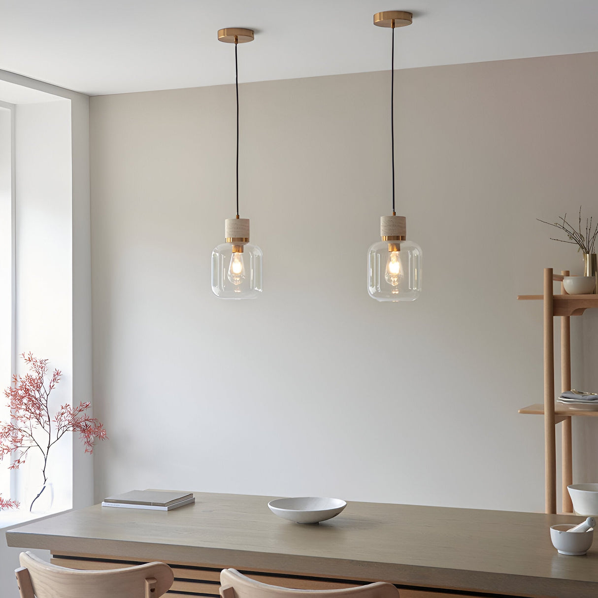 Two Endon Cranstead pendant lights with natural stone tops, brass collars and clear glass shades hanging above a wooden dining table.