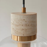 Close-up of Endon Cranstead Pendant Light showing beige travertine stone top, brushed brass collar and clear glass shade against a light background.