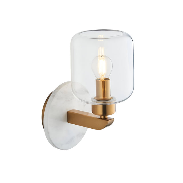 Cranstead Wall Light in Brass & White featuring a round white marble backplate, brass arm and clear glass shade with visible bulb, shown on a plain background.