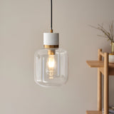 Endon Cranstead pendant light with white stone top, brushed brass collar and clear rounded glass shade with E27 filament lamp, hung near a wooden shelf.