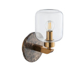 Cranstead Wall Light in brass and brown with round Emperador marble backplate, brass arm, and cylindrical clear glass shade showing bulb.