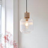 Cranton Pendant Light in Brass & Natural, featuring a ribbed clear glass shade and stone top, hanging in a softly lit room near a window.