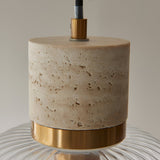 Cranton Pendant Light close-up showing textured stone body, brushed brass collar, ribbed glass shade, and black adjustable cord on a plain background.