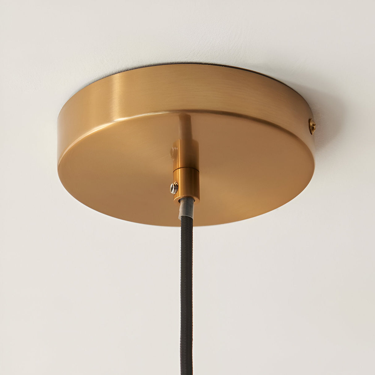 Endon Cranton pendant light brushed brass ceiling rose with black fabric flex cable mounted to a white ceiling.