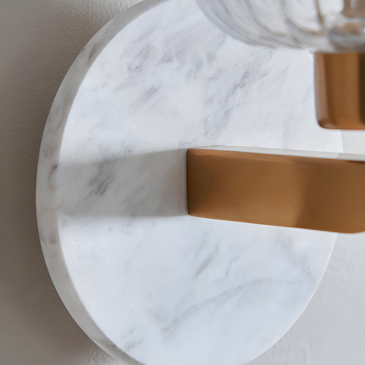Cranton Wall Light in Brass & White, close-up of the white marble backplate with veining and brass arm bracket holding a ribbed glass shade.