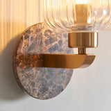 Cranton Wall Light in Brass & Brown, close-up of brown Emperador marble backplate with veining, brass curved arm, and ribbed clear glass shade.