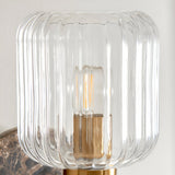 Cranton Wall Light close-up showing the ribbed clear glass shade, brass fitting, and exposed bulb, with a dark marble backplate visible below.