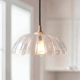 Endon Brackmont Carnation pendant light with scalloped clear glass shade and brushed brass fitting on a black braided cable, hung by a bright window.
