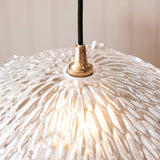 Close-up of the Brackmont Orchid Pendant, a single-light fitting with a textured clear glass shade, brass lamp holder, and black braided flex cable.