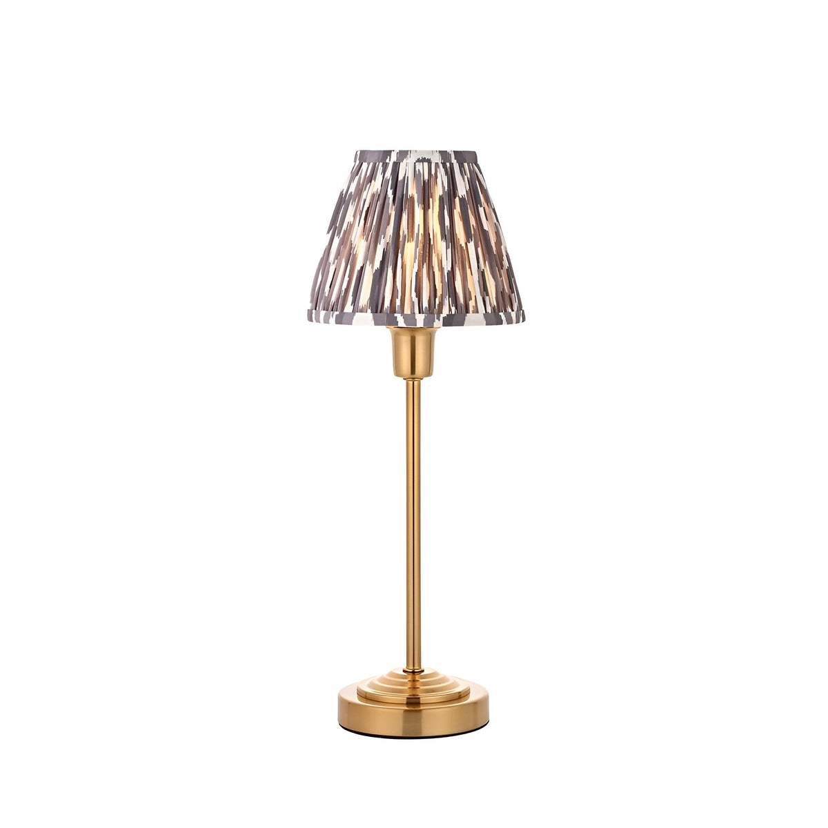 Cliffbourne Ikat Table Lamp with a stepped brass metal base and pleated, tapered grey Ikat-print fabric shade, shown on a plain white background.