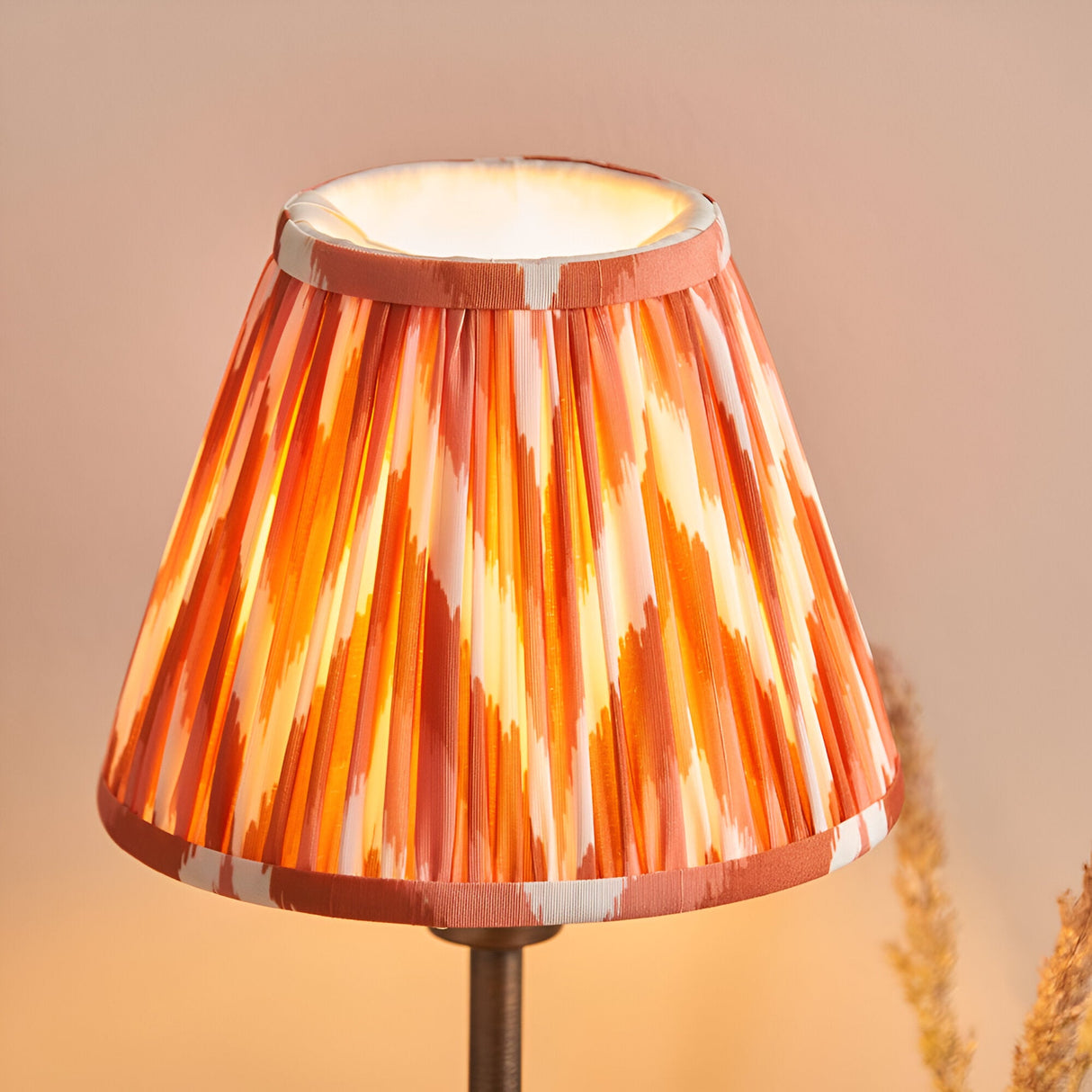 Endon Cliffbourne Zigzag table lamp with a tapered pleated faux silk shade in apricot orange ikat pattern on a slim bronze stem.