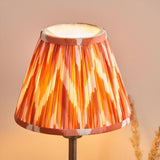 Endon Cliffbourne Zigzag table lamp with a tapered pleated faux silk shade in apricot orange ikat pattern on a slim bronze stem.