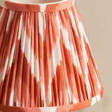 Close-up of the Endon Cliffbourne Zigzag table lamp's pleated shade in apricot orange and white faux silk with taped edge detailing.