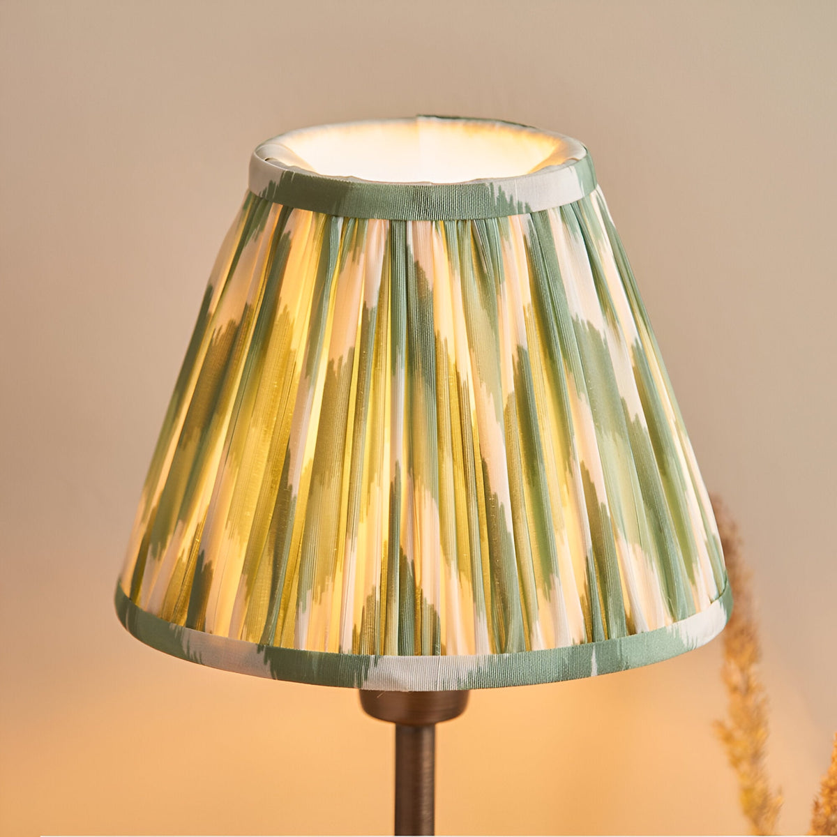 Endon Cliffbourne Zigzag table lamp with illuminated tapered pleated faux silk shade in green and cream ikat pattern on a bronze stem.
