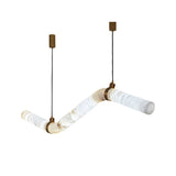 The Zareon LED Medium Articulated Alabaster Suspension Light – Soft White features sculptural, zigzag-shaped frosted glass and brass accents, suspended by black cords from brass mounts for a contemporary statement.