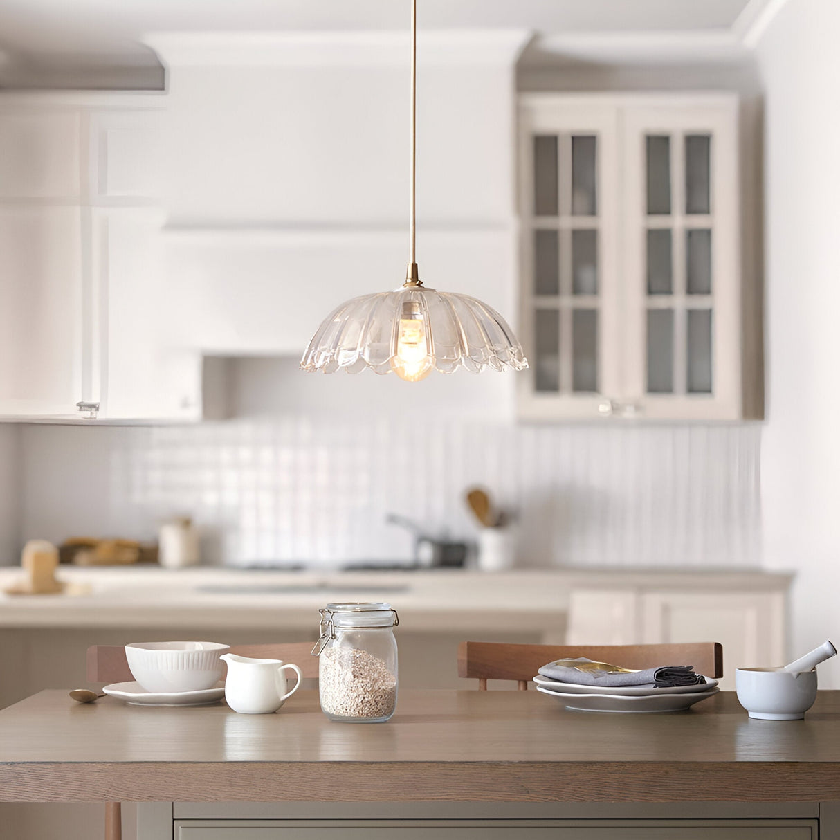 Endon Brackmont Carnation pendant light with clear scalloped glass shade and brass fitting on a natural cable, hung over a kitchen island table.