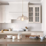 Endon Brackmont Carnation pendant light with clear scalloped glass shade and brass fitting on a natural cable, hung over a kitchen island table.