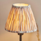 Cliffbourne Ikat Table Lamp in bronze, close-up of the pleated ikat-print shade with taped edges and plain inner lining atop a bronze base.