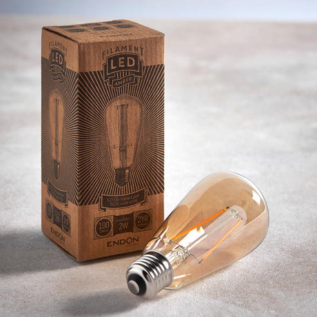 Endon 2W E27 LED filament pear bulb in amber tinted glass beside its printed kraft retail box, shown on a light neutral background.