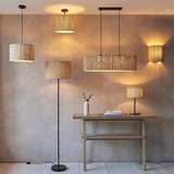 Salcombe Table Lamp with black metal base and woven seagrass drum shade, shown lit on a wooden desk in a lifestyle room setting.