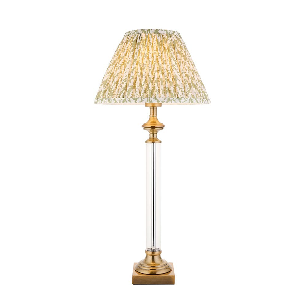 Endon Aldmont Leaf table lamp with a clear glass column, antique brass base and cap, and a pleated green leaf-print shade on a white background.